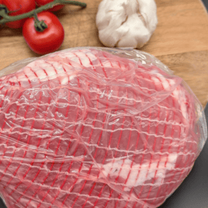 Gammon Slipper Joint on a chopping board with tomato and garlic